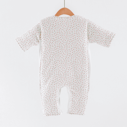 Baby sleepsuit with  pink flower print pattern on a hanger against a white background