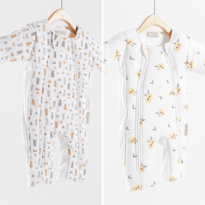 Two baby sleepsuits with different patterns on hangers against a white background