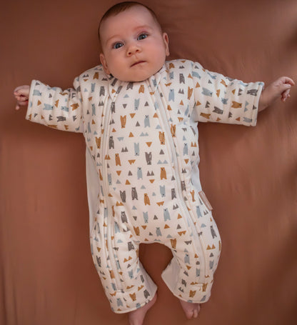 Baby wearing forest friends transition suit in cot on neutral sheet