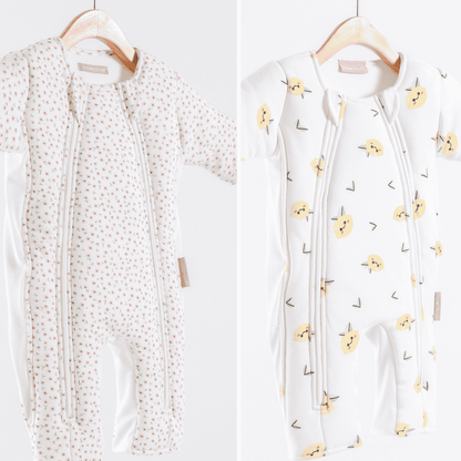 Two infant sleepsuits on hangers with different patterns against a white background