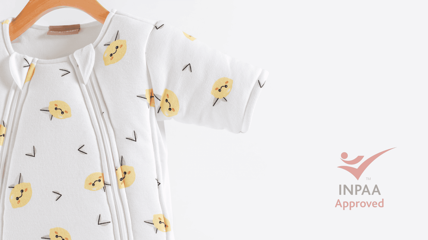 Baby sleepsuit with happy lemon pattern on a white background, featuring INPAA safety approval logo.